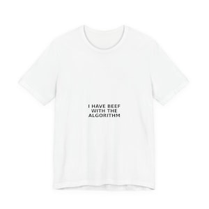May include: A white short-sleeved t-shirt featuring the black text I HAVE BEEF WITH THE ALGORITHM printed in the center of the chest. The garment has a crew neckline and a standard fit, constructed from a plain white fabric with no other patterns.