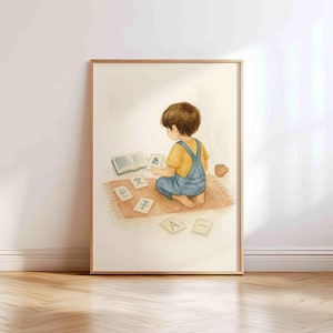 May include: A framed watercolor print depicts a child in a yellow shirt and blue overalls studying Japanese characters. The child sits on a rug surrounded by flashcards and a book. A small cup sits nearby.