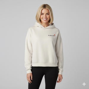 May include: Cream-colored hoodie with the word "mama" embroidered in black script with a red heart. The hoodie has a hood and long sleeves. The model is wearing black leggings.