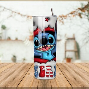 K&ouml;nnte beinhalten: Edelstahlbecher mit einem Cartoon-Charakter mit blauem K&ouml;rper, gro&szlig;en Augen und einem breiten Grinsen. Das Design enth&auml;lt rote und wei&szlig;e Akzente, mit dem Wort "USA" in einer patriotischen Schriftart. Ein silberner Strohhalm ist eingesetzt.