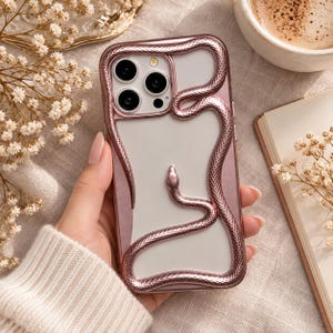 May include: A rose gold phone case featuring a three-dimensional metallic snake relief that winds around the camera module and across the back of the clear, semi-transparent protective cover for a smartphone device.