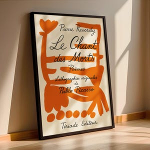 May include: A black framed poster with an orange abstract design. The text on the poster reads "Pierre Reverdy Le Chant des Morts Po&egrave;mes Lithographies originales de Pablo Picasso  T&eacute;riade Editeur".