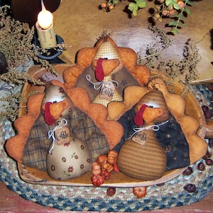 May include: Three handcrafted turkey decorations with orange and brown fabric, each with a red wattle and a tag that says "Gobble". The turkeys are arranged on a wooden tray with small orange pumpkins.