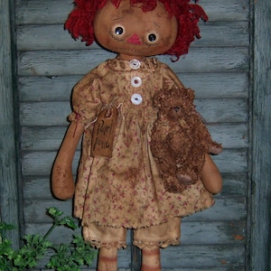 May include: A rag doll with red yarn hair, wearing a floral print dress and holding a brown teddy bear. The doll has a tag that says "Pearl Anne".