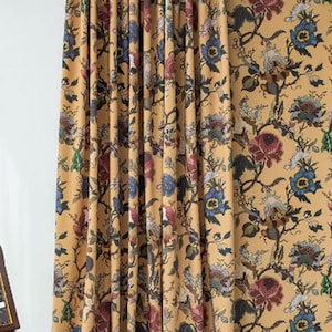 Puede incluir: Cortinas florales de color mostaza con papel pintado a juego. Las cortinas presentan un patrón repetitivo de flores azules, rojas y verdes. El papel pintado tiene el mismo diseño floral.