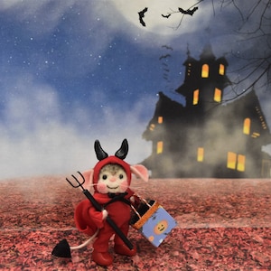 May include: A small, felt mouse dressed as a devil for Halloween, holding a trick-or-treat bag and a pitchfork. The mouse is standing in front of a silhouette of a spooky house with a starry night sky in the background.