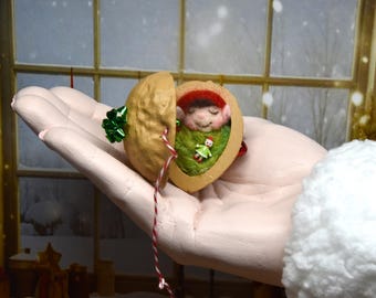Gefilzter kleiner Weihnachtself schlafend in einer Walnussschale