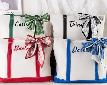 May include: White canvas tote bags with colored trim and matching decorative bows. Each bag has a different color trim and bow, with names embroidered on the front in a matching color. The bags are personalized and suitable for various occasions.