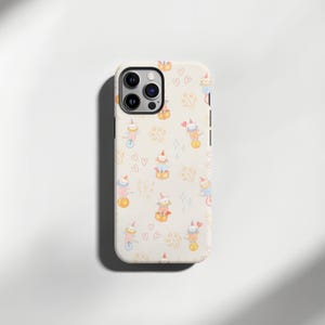 Op de afbeelding: Een telefoonhoesje met een grillig patroon van circuskatten. De crèmekleurige hoes heeft herhaalde illustraties van katten met clownshoeden die op een eenwieler rijden, op dozen balanceren en jongleren. Harten en vuurwerk maken het speelse ontwerp compleet.