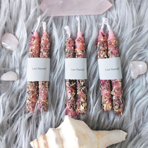 May include: Three sets of pink and white herbal candles with the text "Love Yourself" on the labels.