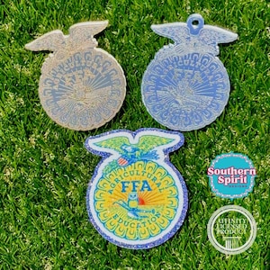 May include: Three circular FFA emblems featuring an eagle, a cross-section of an ear of corn, an owl, a plow, and rising sun. Two emblems have a metallic finish, while the third is colorful with glitter. Includes Southern Spirit Designs text.