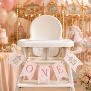 Può includere: Un seggiolone bianco decorato con uno striscione a righe rosa e bianche che riporta la parola ONE in lettere maiuscole rosa e illustrazioni di una giostra sui gagliardetti, su uno sfondo sfocato di una giostra e palloncini.