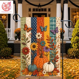 May include: A vertical garden flag featuring a patchwork design of striped panels in green, blue, orange, and yellow. The flag displays a central orange pumpkin, a smaller blue pumpkin, and a white pumpkin, surrounded by flowers, leaves, and butterflies.