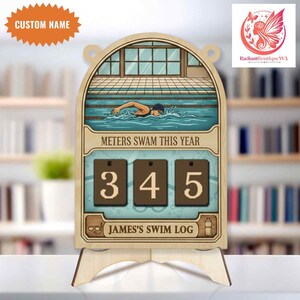 May include: Wooden swim log with a swimmer illustration. The log displays "METERS SWAM THIS YEAR" and a counter showing "345". It includes the text "JAMES'S SWIM LOG" and a space for a custom name.