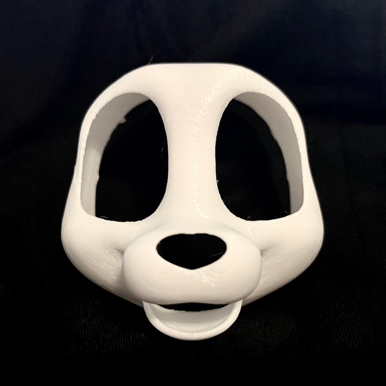 May include: A white, 3D-printed mask with large eye openings and a rounded snout. The mask has a smooth texture and is designed to fit over the face. The design resembles a cartoon animal.