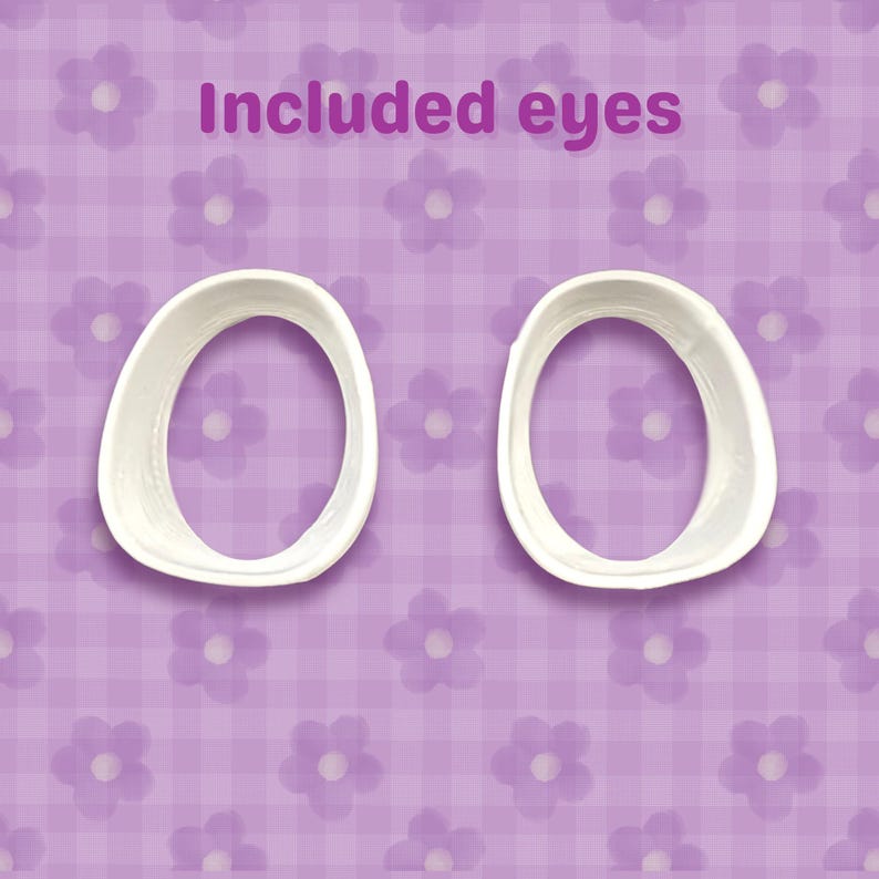 May include: Two white, oval-shaped eye molds are shown against a purple floral background. The text "Included eyes" is written in a purple font above the molds. The background has a checkered pattern with flower designs.