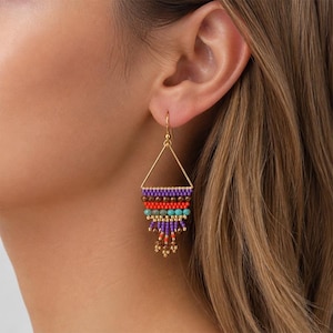 May include: A gold-toned triangle earring featuring a multi-strand fringe design. The earring is composed of small beads in purple, brown, red, and turquoise, arranged in horizontal rows that taper into a dangling, layered beaded fringe.