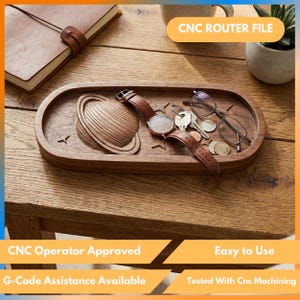 May include: A wooden tray with a carved planet design, holding a watch, keys, glasses, and coins. The tray is oval-shaped and sits on a wooden table. The text "CNC ROUTER FILE" is visible.