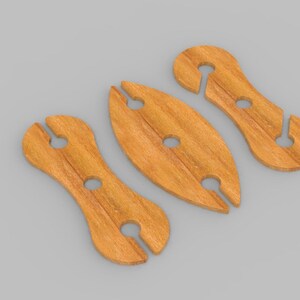 May include: Three wooden wine glass holders in a light brown color. Each holder has a unique shape with a circular hole and a slot for the stem of a wine glass. The holders are arranged on a gray surface.