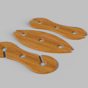 May include: Three wooden wine glass holders in a light brown color. The holders have a unique design with a slot for the glass stem and a hole for the glass base. The holders are arranged on a gray surface.