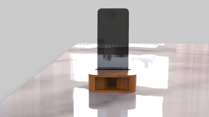 May include: A modern, minimalist phone stand. The stand features a dark gray rectangular screen supported by a rounded, light brown wooden base with a rectangular cutout. The stand is on a white surface.