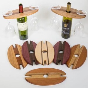 May include: Wooden wine bottle and glass holders with a natural finish. The holders have a circular hole for the bottle and slots for wine glasses. Several wooden coasters in various wood tones are also included.