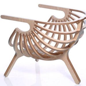 May include: A light-coloured wooden chair with a distinctive, open design. The chair has curved wooden slats forming the back and seat, supported by angled legs. The armrests extend outwards, creating a modern, artistic aesthetic.