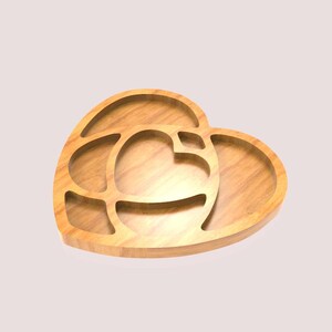 May include: A heart-shaped wooden serving tray with multiple compartments. The tray is made of light-coloured wood and features a heart-shaped design within a larger heart shape. The compartments are ideal for serving snacks or appetizers.