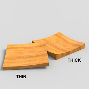 K&ouml;nnte beinhalten: Zwei quadratische Holzobjekte mit geschwungenem Design. Eines ist mit "THIN" (d&uuml;nn) und das andere mit "THICK" (dick) beschriftet. Das Holz hat eine nat&uuml;rliche Maserung und eine warme, hellbraune Farbe. Die Objekte sind wahrscheinlich dekorativ oder funktional.