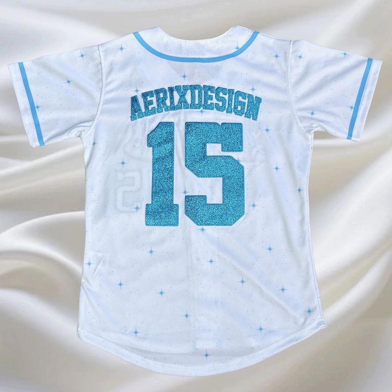 May include: White baseball jersey with light blue trim and accents. The jersey features the text "AERIXDESIGN" above the number "15" in a glittery blue. Small blue star patterns are scattered across the jersey.
