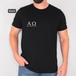 May include: Black crew neck t-shirt with the white text "AΩ ALPHA AND OMEGA" printed on the front. The shirt is a solid black colour.
