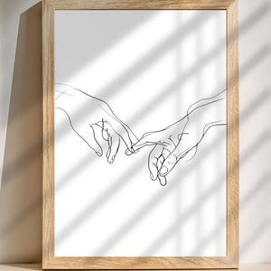 May include: A black and white line drawing of two hands reaching towards each other, with fingers intertwined. The drawing is framed in a light wood frame.