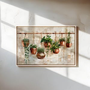 May include: A framed watercolor painting depicts a row of hanging copper pots filled with various green plants. The pots are suspended from a copper rod against a backdrop of square, off-white tiles. The artwork is set in a light-colored frame.