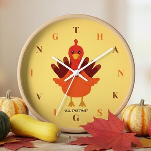 May include: A round wooden clock with a yellow face featuring a cartoon turkey illustration. The clock hands point to the time, and the words "ALL THE TIME" are printed at the bottom. Pumpkins and fall leaves surround the clock.