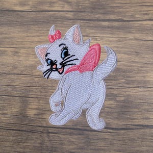 May include: Embroidered patch featuring a cartoon cat with a pink bow on its head and a pink bow around its neck. The cat is light gray with blue eyes and black whiskers. The patch is designed to be ironed on.