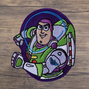 May include: Embroidered patch featuring Buzz Lightyear from Toy Story. The patch showcases Buzz in his signature green, white, and purple spacesuit, with a blue helmet visor. The design is set against a purple background.