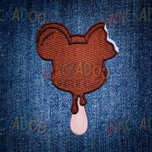 May include: A brown embroidered patch in the shape of a cartoon ice cream bar with a bite taken out of it. The ice cream is dripping, with a pink and white drip at the bottom. The patch is on a blue denim background.