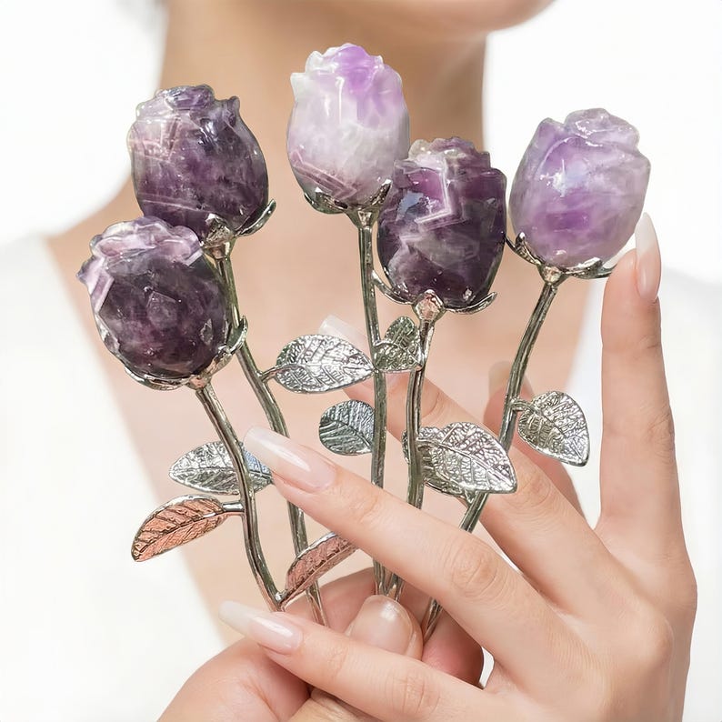Peut inclure: Cinq sculptures de roses en am&eacute;thyste avec des tiges et des feuilles argent&eacute;es. Les p&eacute;tales de rose sont sculpt&eacute;s dans du cristal violet et blanc. Les tiges sont tenues dans une main.