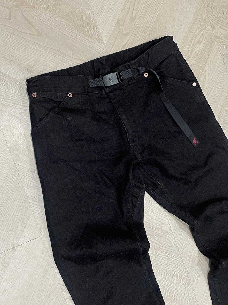 Puede incluir: Pantalones vaqueros negros con cintur&oacute;n incorporado. Los pantalones tienen un corte de pierna recto y presentan un peque&ntilde;o logotipo rojo cerca del bolsillo. El cintur&oacute;n tiene una hebilla negra. Los pantalones est&aacute;n hechos de un material resistente.