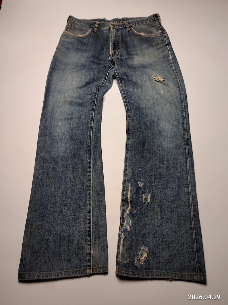 Peut inclure: Jean bleu d&eacute;lav&eacute; avec des d&eacute;tails us&eacute;s, notamment des d&eacute;chirures et des patchs us&eacute;s. Le jean a une conception classique &agrave; cinq poches et une coupe d&eacute;contract&eacute;e. Le denim montre des signes d'usure et de d&eacute;coloration.