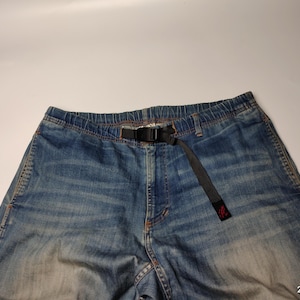 May include: Blue denim trousers with a black belt. The trousers have a faded wash and a relaxed fit. The belt is made of a durable fabric and features a black buckle. The trousers are a casual style.