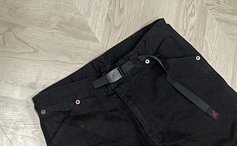 Puede incluir: Pantalones negros con cintur&oacute;n negro integrado y hebilla. Los pantalones tienen un dise&ntilde;o de pierna recta y cuentan con varios remaches de color cobre. Los pantalones est&aacute;n hechos de un material duradero y son adecuados para actividades al aire libre.
