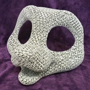 May include: A white, three-dimensional printed animal mask base featuring a complex, porous, web-like lattice structure. The mask has two large, hollow eye sockets and a protruding snout area with an open mouth section, showcasing a detailed mesh.
