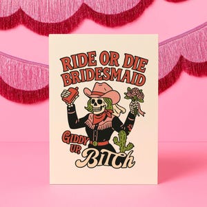 Könnte beinhalten: Ein cremefarbener Druck mit einem Skelett-Cowgirl mit grünen Haaren, einem rosa Cowboyhut und einem roten Bandana. Der Text lautet "Ride or Die Bridesmaid" und "Giddy Up Bitch" in einer Retro-Schriftart. Das Cowgirl hält eine Flasche und Blumen.