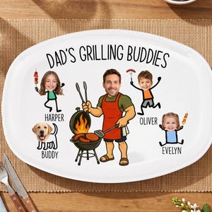 Könnte beinhalten: Ovale weiße Platte mit dem Text "DAD'S GRILLING BUDDIES" und Cartoon-Illustrationen eines grillenden Mannes, drei Kindern und einem Hund. Die Platte befindet sich auf einer gewebten Tischmatte auf einem Holztisch.