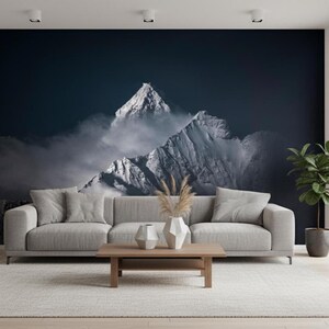 Könnte beinhalten: Ein Wohnzimmer mit einem Wandbild eines schneebedeckten Bergmassivs. Vor dem Wandbild steht ein graues Sofa mit passenden Kissen. Ein Holztisch, ein Teppich und eine Topfpflanze vervollständigen die Einrichtung.