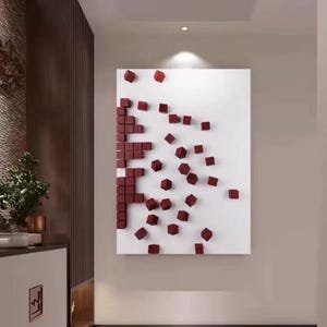 K&ouml;nnte beinhalten: Modernes abstraktes Wandkunstwerk mit wei&szlig;em Hintergrund und einem Muster aus weinroten 3D-W&uuml;rfeln. Die W&uuml;rfel sind in einem pixelartigen Design angeordnet und erzeugen einen einzigartigen visuellen Effekt. Das Kunstwerk ist an einer Wand montiert.