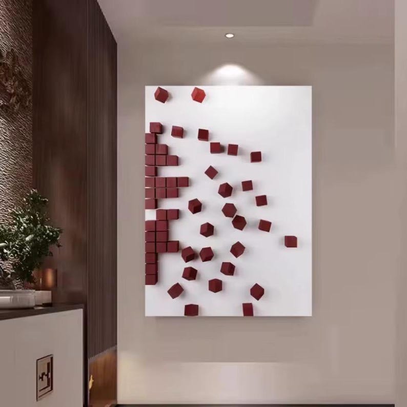 K&ouml;nnte beinhalten: Modernes abstraktes Wandkunstwerk mit wei&szlig;em Hintergrund und einem Muster aus weinroten 3D-W&uuml;rfeln. Die W&uuml;rfel sind in einem pixelartigen Design angeordnet und erzeugen einen einzigartigen visuellen Effekt. Das Kunstwerk ist an einer Wand montiert.