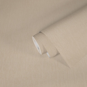 Könnte beinhalten: Eine Rolle beigefarbener Tapete mit einem dezent strukturierten Muster. Die Tapete ist teilweise abgerollt und zeigt die weiße Rückseite. Die neutrale Farbe und das schlichte Design deuten auf ein vielseitiges Wohnaccessoire hin.