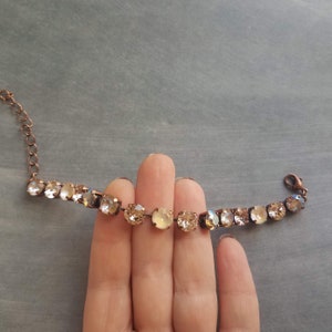 May include: A delicate bracelet featuring a series of round, champagne-colored crystals set in a copper-toned metal chain. The crystals vary slightly in color, creating a subtle sparkle. The bracelet is designed with a lobster clasp for secure fastening.